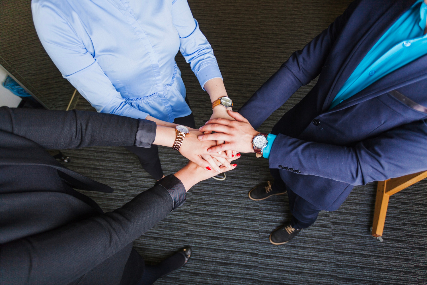 People standing in office holding hands together